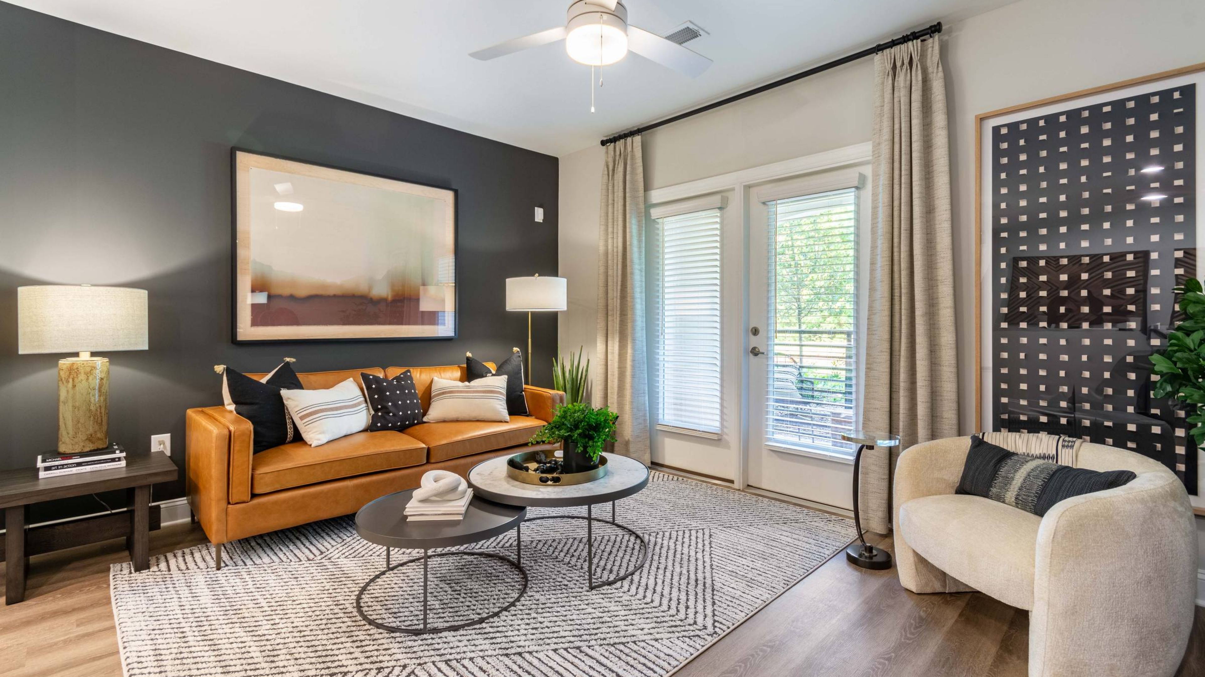 Hawthorne Northwest bright and airy bedroom featuring a large window, modern ceiling fan, and a cozy bed with stylish decor and a mounted TV.