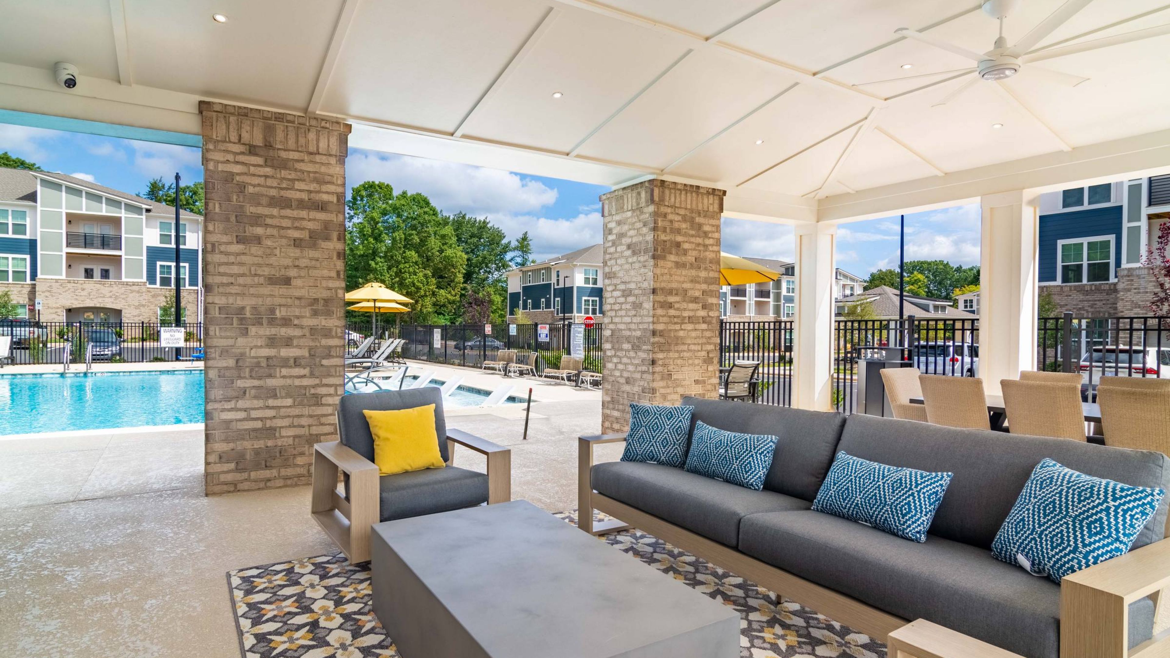 Hawthorne Northwest open-plan kitchen and living room featuring modern cabinetry, a large island, pendant lighting, and a cozy seating area with a wall-mounted TV and access to a balcony.